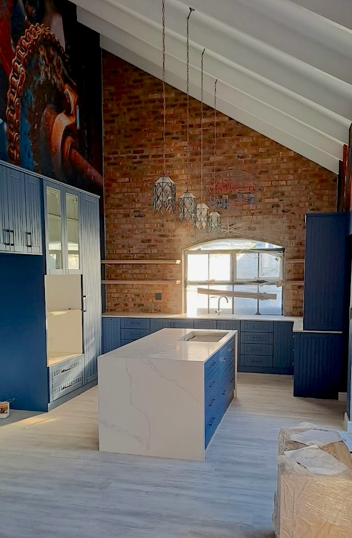 Custom blue kitchen with a stone island and exposed brick